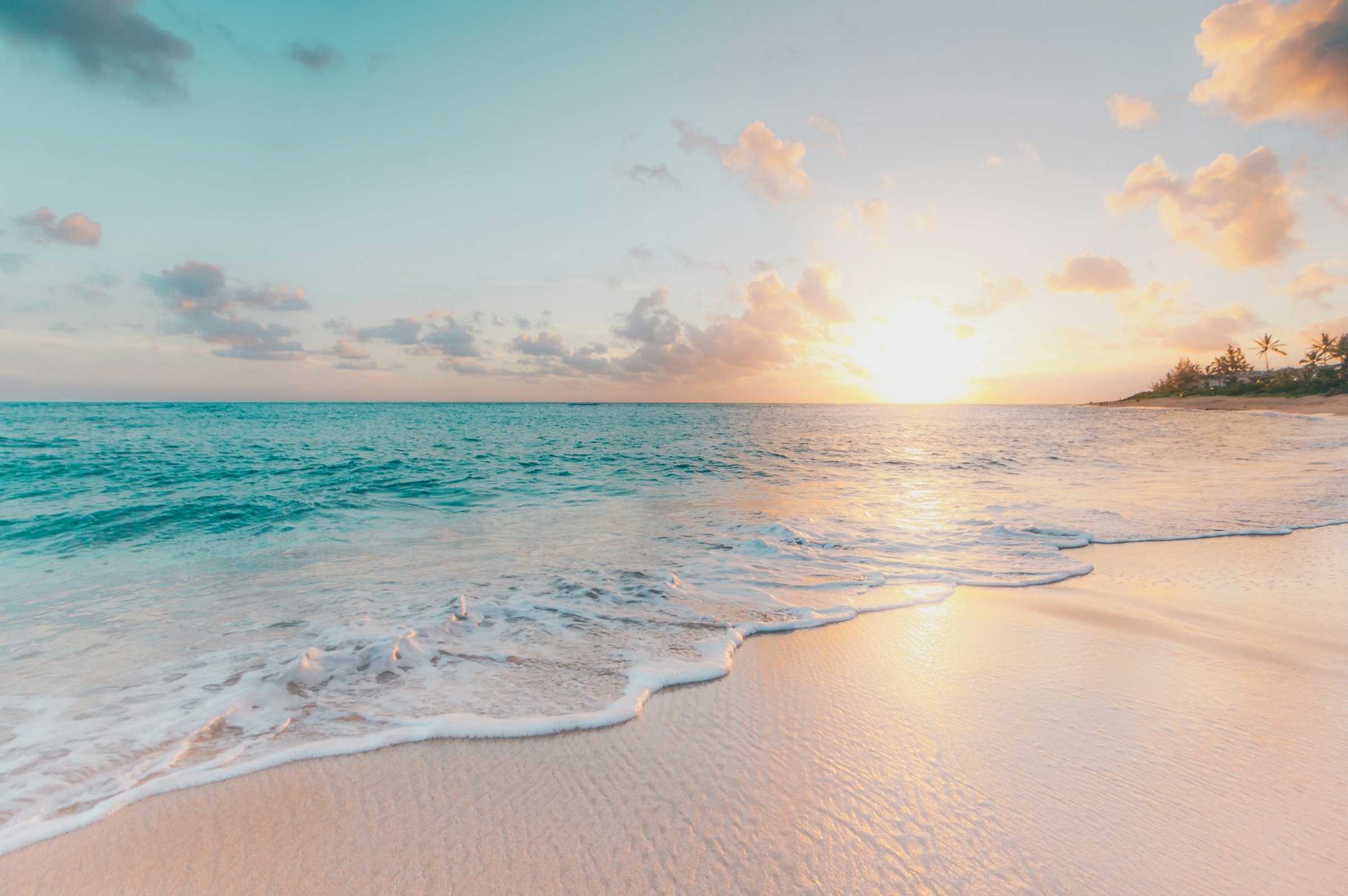 Gentle waves washing onto a sandy beach at golden-hour sunset